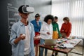 Using modern technologies. Young asian man in casual clothes wearing virtual reality glasses while his colleagues Royalty Free Stock Photo