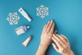 Using moisturizing hand cream during winter season. Female hands smearing white cream on the blue background next to different Royalty Free Stock Photo