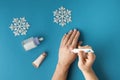 Using moisturizing hand cream during winter season. Female hands smearing white cream on the blue background next to different Royalty Free Stock Photo