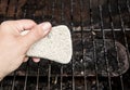 Using natural pumice stone to scrub charred food deposits and rust from BBQ grill metal grid.