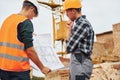 Using paper document with plan on it. Two construction workers in uniform and safety equipment have job on building together Royalty Free Stock Photo