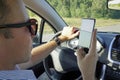 Using a phone in a car texting while driving concept for danger of text message and being distracted. A young man looks at the Royalty Free Stock Photo