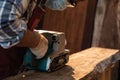 Using sanding machine belt sander to level surface wood. Carpenter use a hand-held electric sanding machine in carpentry workshop