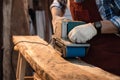 Using sanding machine belt sander to level surface wood. Carpenter use a hand-held electric sanding machine in carpentry workshop Royalty Free Stock Photo
