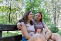 Using a smartphone.Mom and her teenage daughter have fun laughing on a walk in a summer park. Royalty Free Stock Photo