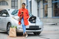 Using smartphone while waiting. African American girl on the electric cars charge station at daytime. Brand new vehicle