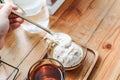 Using spoon eating brown cup with salted caramel ice cream and a glass of water on wooden vintage table.Cold dessert in cup. Busin