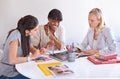 Using their collective creativity. three businesswoman gathered around a table in the office.