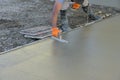 Using a trowel worker plasters a wet concrete cement floor after it has been poured Royalty Free Stock Photo