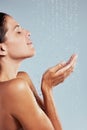 Using water sparingly. a young woman taking a shower against a grey background.