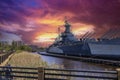 The USS North Carolina surrounded by lush green trees and grass and powerful clouds at sunset on a summer day Royalty Free Stock Photo