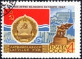 Post stamp printed in the USSR shows Coat of Arms, Flag and monument Latvian SSR, serie `50 years of the Great October`.Philately