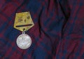 The USSR medal for military merits of the Patriotic war lies on the fabric of the plaid.