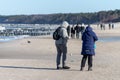 Ustka, Pomorskie / Poland - February, 22, 2019: People walking along the beach on the seashore. A winter walk in sunny weather Royalty Free Stock Photo