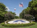 UT Arlington symbol in a garden of stones and plants with American, Texas, and University flags flying in Arlington, Texas.