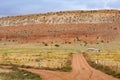 Utah landscape with huge mesa landform dominating small buildings and dirt road