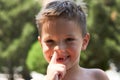 ute little boy enjoying picking his nose, close-up.