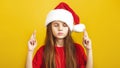 ÃÂ¡ute little girl wearing Christmas Santa hat make a wish standing isolated over yellow background