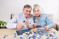 Cute Senior couple solving jigsaw puzzle together at home Royalty Free Stock Photo