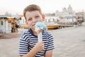 ÃÂ¡ute seven-year-old boy in a striped t-shirt sits on the waterfront in Venice in the evening and eats gelato (ice cream