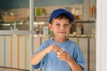 ÃÂ¡ute 6-year-old boy in a blue T-shirt eats ice cream gelato with a spoon from a glass in a gelateria in Rome. Traditional