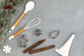 Utensils for Christmas cooking or baking with spoon, whisk, icing piping bag and cookie cutters with fir branch on concrete.