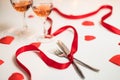 Valentine`s day display of a dinner preparation with cutlery, red ribbon, glasses of wine and heart symbols Royalty Free Stock Photo