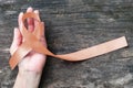 Uterine and Gynecologic Cancer Awareness peach color ribbon on womanÃ¢â¬â¢s hand and aged wood isolated with clipping path