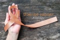 Uterine and Gynecologic Cancer Awareness peach color ribbon on womanÃ¢â¬â¢s hand support and aged wood with clipping path