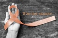 Uterine and Gynecologic Cancer Awareness peach color ribbon on woman`s hand support and aged wood with clipping path