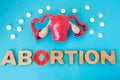 Uterus model with pills as medical abortion concept photo . 3D figure of uterus with ovaries is on blue background with crumbled p