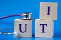 UTI - acronym on wooden large cubes on blue background with stethoscope