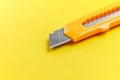 A utility knife with a retractable segmented blade on a creative yellow background Royalty Free Stock Photo