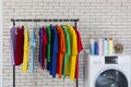 Utility room with washing machine, cleaning equipment and colorful t-shirt. Concept of a big washing. Clothes hanging near washing