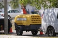 Utility van with yellow compressor trailer with jackhammer machine on road construction site