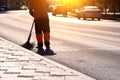 A utility worker with a broom sweeps the street in the morning in the city