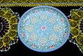 Uzbek traditional serving bowl souvenir placed on embroidered carpet suzani, painted ceramics