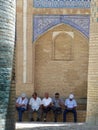 Uzbeks sitting in front of the wall of a Madrasah in Khiva in Uzbekistan