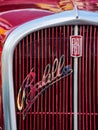front close-up of a red fiat 508 balilla oldtimer with chrome logo on the grille. sunny outdoor