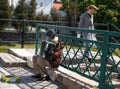 UZHHOROD, UKRAINE - MAY 07, 2020: Street poor musician in facial mask playing accordion to earn money in Uzhhorod