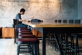 Vacancy chairs and wooden table with blurred unidentified man working with his laptop in background Royalty Free Stock Photo
