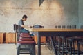 Vacancy chairs and wooden table with blurred unidentified man working with his laptop in background at the coffee shop. Royalty Free Stock Photo