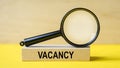 VACANCY word through magnifying glass on wooden background