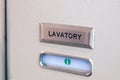 Vacant green sign, vacant symbol on an airplane lavatory door. Raised, brushed metal lavatory sign, recessed plastic vacant sign.