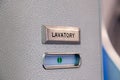 Vacant green sign, vacant symbol on an airplane lavatory door. Raised, brushed metal lavatory sign, recessed plastic