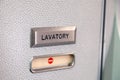 Vacant red sign, occupied symbol on an airplane lavatory door. Raised, brushed metal lavatory sign, recessed plastic vacant sign.
