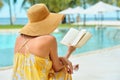 Vacation Beach Summer Holiday Concept. Beautiful woman in yellow dress reading book resting in beach Royalty Free Stock Photo