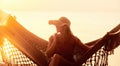 Vacation Beach Summer Holiday Concept. Young pretty woman in hat sitting in hammock at sunset Royalty Free Stock Photo