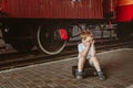 Vacation with children. A boy sits on a suitcase on the platform at the train station. A train is waiting, it is boring for him to