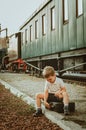 Vacation with children. A boy sits on a suitcase on the platform at the train station. A train is waiting, it is boring for him to